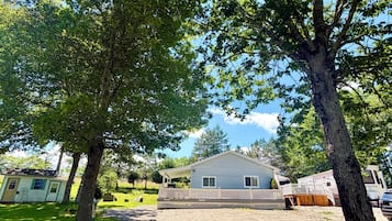 A single-story house with a covered porch, a gravel driveway, and a grassy yard.