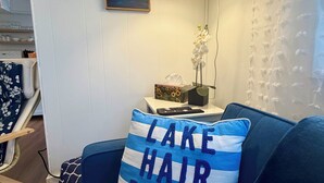 Una sala de estar con un sofá azul, una lámpara, un cuadro y una ventana con vistas.