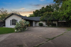 A single-story house with a brick facade, a front yard, and a driveway. - Woodstone Casita~Lush backyard~Central location (Austin)