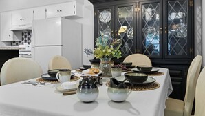 A dining table set with bowls, plates, and a vase of flowers, surrounded by chairs.