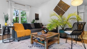 A living room with a sofa, a coffee table, a chair, a lamp, and a large plant.