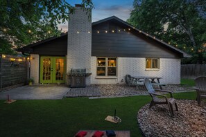 A house with a brick exterior, a green door, a barbecue grill, and outdoor seating. - Woodstone Casita~Lush backyard~Central location (Austin)