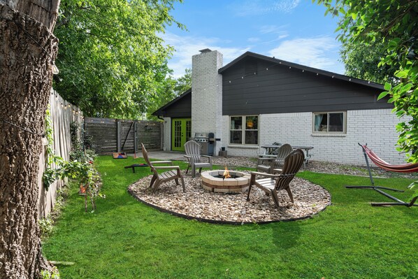 A backyard with a fire pit, outdoor seating, and a hammock. - Woodstone Casita~Lush backyard~Central location (Austin)
