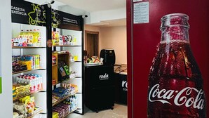 Ein Ladeninneres mit Regalen voller verschiedener Produkte, einem Coca-Cola-Kühlschrank und einem Gefrierschrank im Vordergrund.