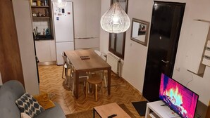 A living room with a sofa, a coffee table, a TV, and a dining area with a table and chairs.