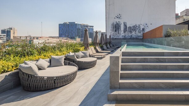 Une terrasse sur le toit avec des sièges extérieurs, une piscine et une vue sur la ville.