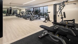 Une salle de sport équipée de machines de cardio, de matériel de musculation et d’une zone dédiée aux exercices de développé couché.
