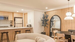 Une cuisine moderne avec des meubles en bois, un îlot central doté de tabourets et un coin repas avec une table ronde et des chaises.
