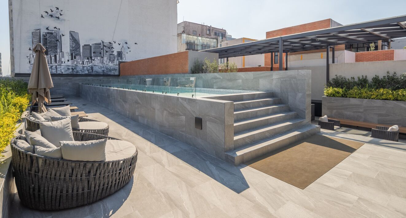 Une terrasse sur le toit avec une piscine, des sièges extérieurs et une fresque représentant un paysage urbain.