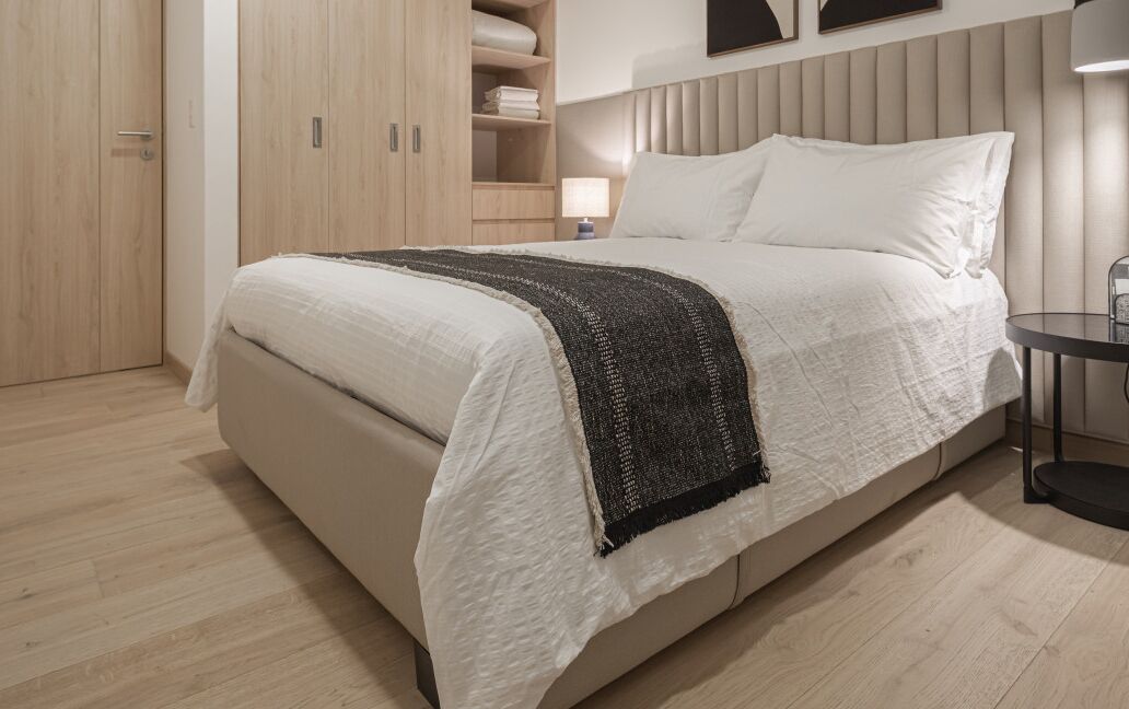 A bedroom with a bed, a bedside table, a lamp, and a wardrobe.