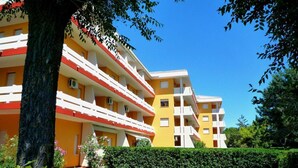 A multi-story hotel with balconies, a well-maintained garden, and a clear blue sky.
