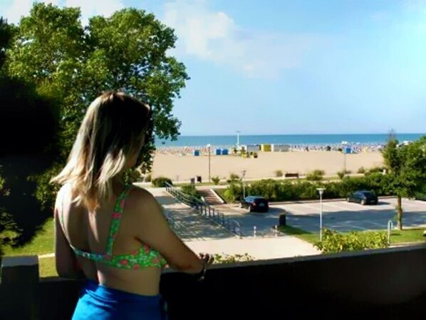 A view of a beach with a parking area and a building in the foreground.