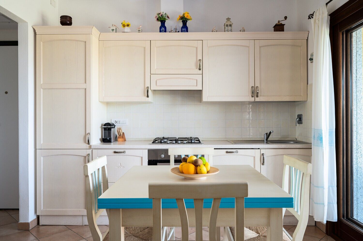 A kitchen with white cabinets, a stove, and a dining table with chairs.