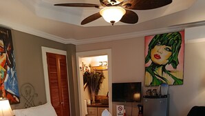Une chambre d’hôtel avec deux lits, un ventilateur de plafond, une télévision, un tableau et un panneau « interdiction de fumer ».
