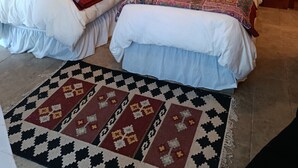 Une chambre double avec deux lits, un tableau au mur, un ventilateur de plafond et un tapis à motifs.
