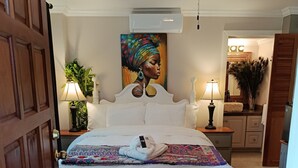 Une chambre à coucher avec un lit, un ventilateur de plafond, un tableau et une table de chevet avec une lampe.