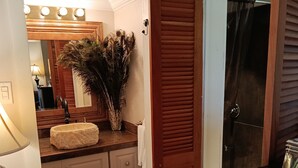 Une salle de bain équipée d’un meuble-lavabo, d’un lavabo, d’un miroir et d’un espace douche.
