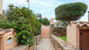 A stone pathway leading to a building with a stone wall and a wooden door.