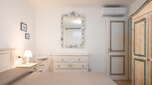 A bedroom with a bed, a dresser, a mirror, a nightstand, and a wardrobe.