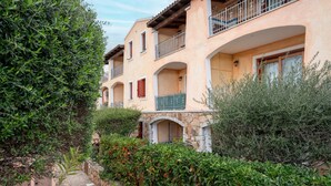 A multi-story building with balconies, stone archways, and lush greenery.