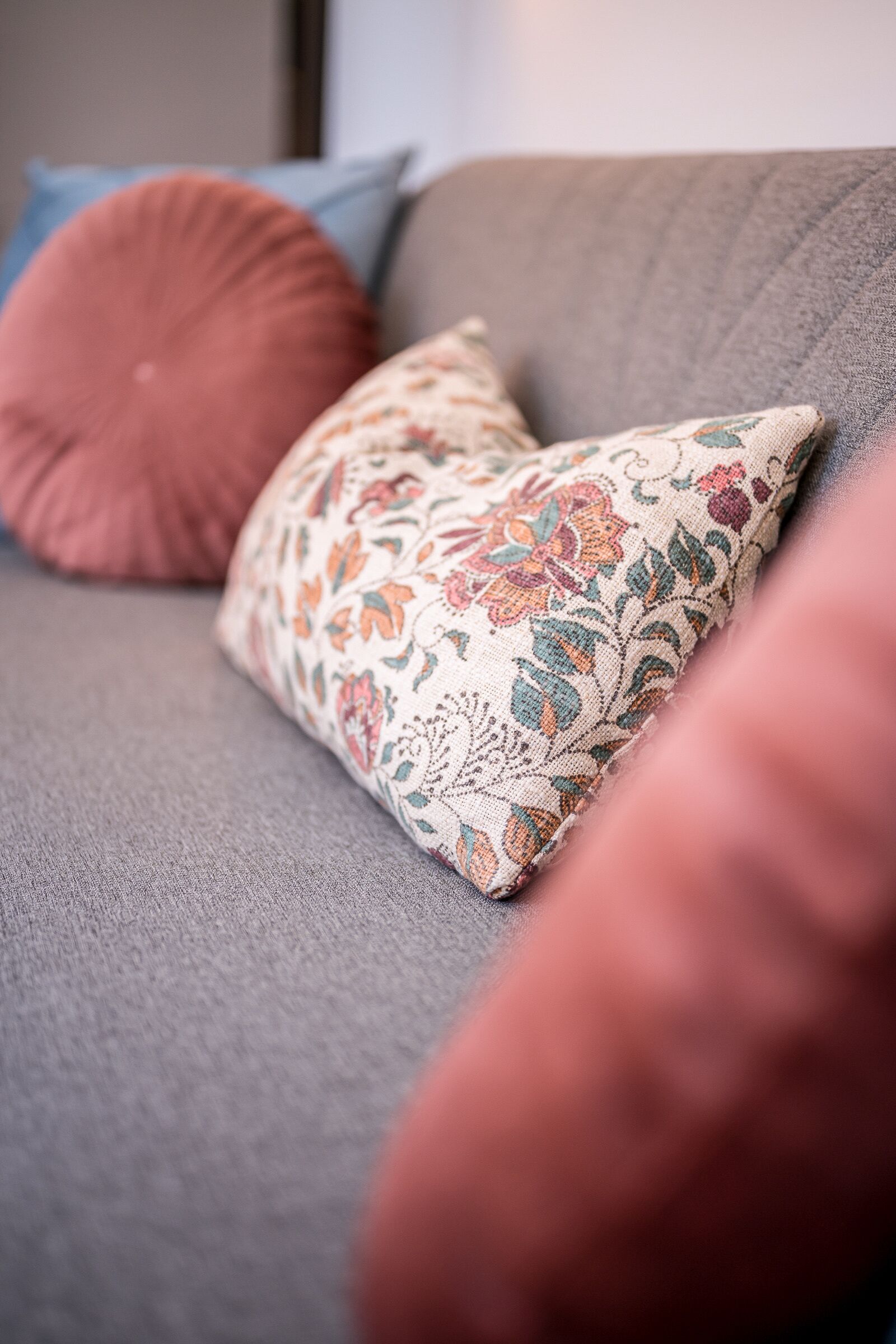 Ein Detailaufnahme eines Sofas mit einem Kissen mit Blumenmuster und einem einfarbigen Kissen.