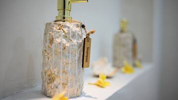A bathroom with a white sink, a gold faucet, and a bottle of shampoo.