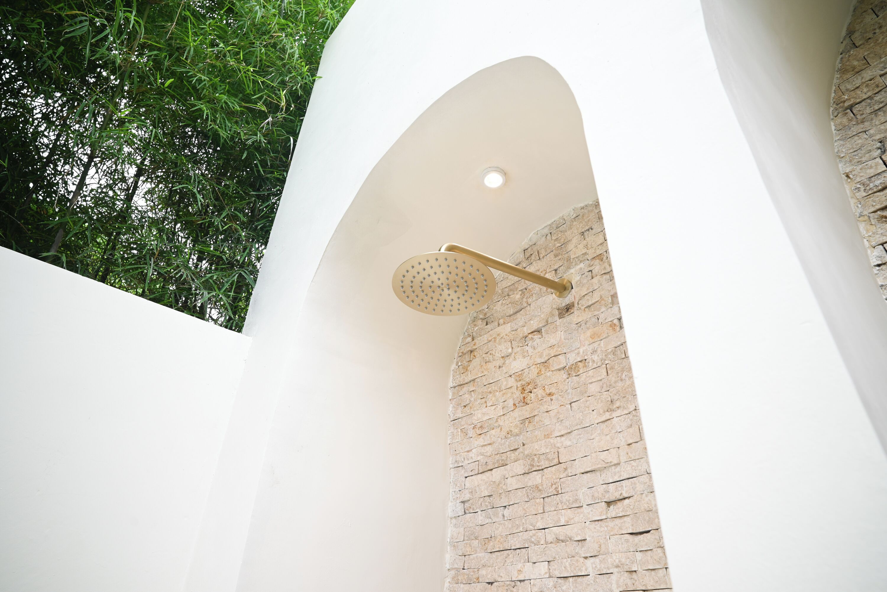 A shower area with a brick wall and a white ceiling.
