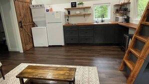 Cocina moderna con armarios oscuros, un refrigerador blanco y repisas de madera.