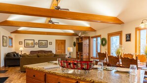 Una cocina amplia con vigas de madera, encimeras de granito y una zona de comedor con sillas y mesa de madera.