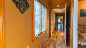 Un pasillo con pisos de madera, ventanas amplias y una puerta que da a otra habitación.