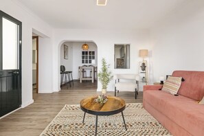A modern living room with a round wooden coffee table, a red sofa, and a dining area in the background. - Skyline Heights by Homie (Funchal)