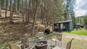 Un chalet rustique doté d’un foyer extérieur et de sièges pour profiter de l’extérieur.