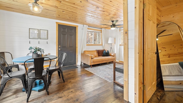 Un intérieur en bois comprenant un coin repas, un canapé et un ventilateur de plafond.