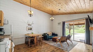 A cozy cabin interior with a wooden dining table, a sofa, and a kitchen area with a refrigerator and stove. - The Minnesota Ridge Cabin (Keystone)
