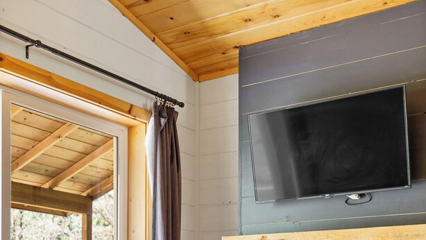 A cozy room with a fireplace, a television mounted on the wall, and a wooden ceiling. - The Minnesota Ridge Cabin (Keystone)