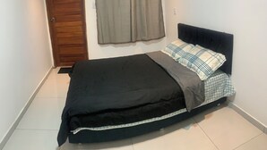 Un dormitorio con una cama, una puerta de madera y cortinas grises.