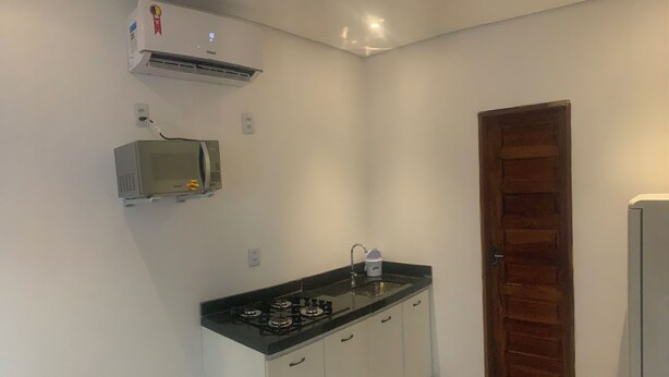 Una cocina pequeña con estufa a gas, microondas y cafetera.