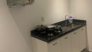 Una cocina compacta con estufa a gas, microondas y aire acondicionado integrado.