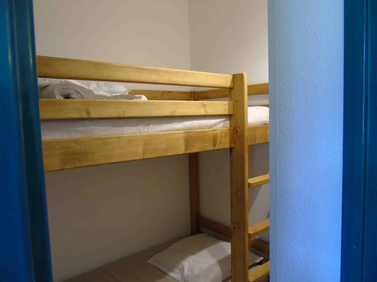 A bunk bed with a wooden frame and white bedding.