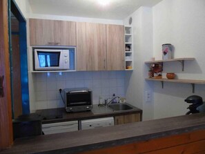 A compact kitchen with a microwave, toaster, and a sink.