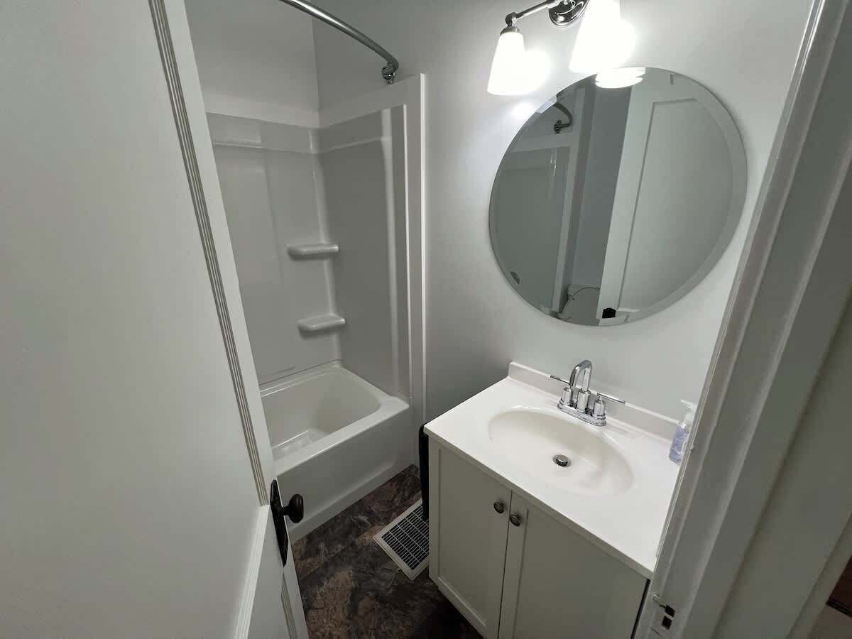 A bathroom with a bathtub, a sink, and a mirror.