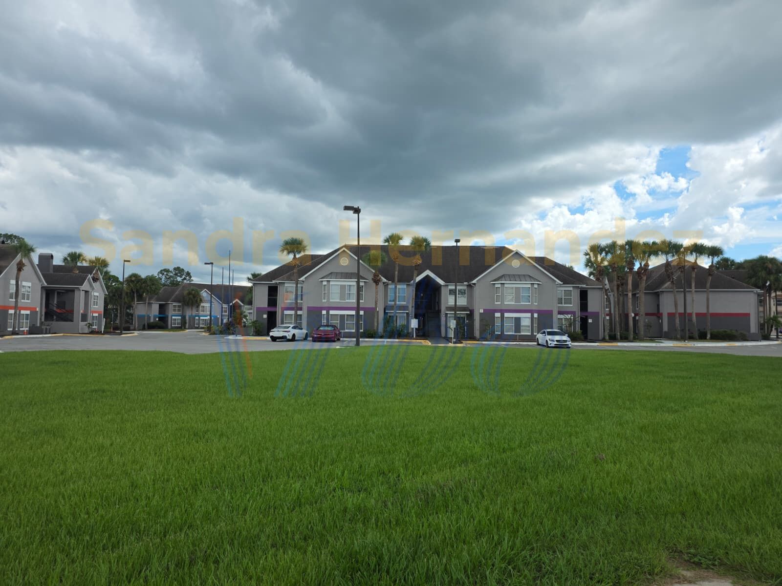 Conjunto residencial con varias casas, estacionamiento y un área verde frontal.