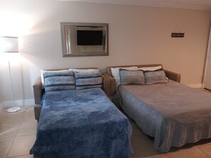 Quarto com duas camas, televisão e abajur.