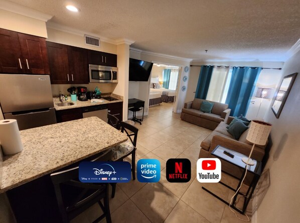 A modern kitchen with granite countertops, a built-in microwave, and a stainless steel refrigerator.