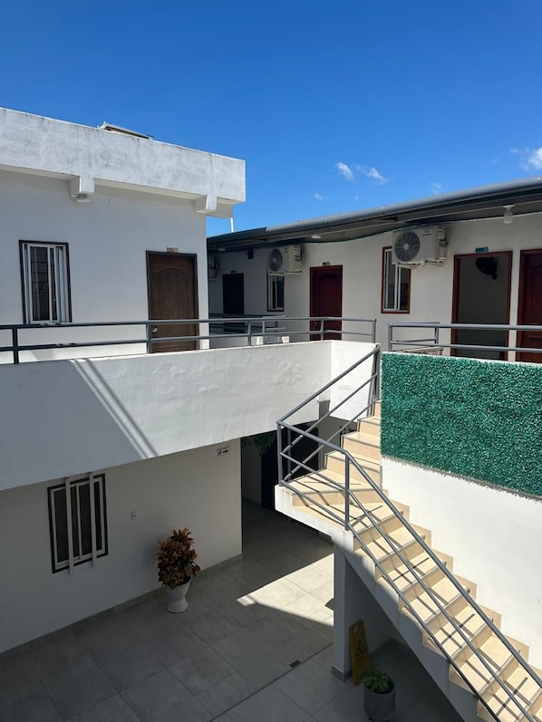 A modern building with a flat roof, a staircase with metal railings, and a green artificial turf area. - Hosteria Altamar (Tolú)