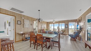 A dining area with a wooden table and chairs, a ceiling fan, and a view of the outdoors.