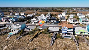 A coastal residential area with multiple two-story houses, a beach access walkway, and a clear view of the ocean.
