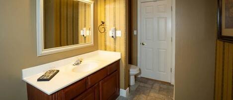 A bathroom with a large mirror, a double sink vanity, a toilet, and a door.