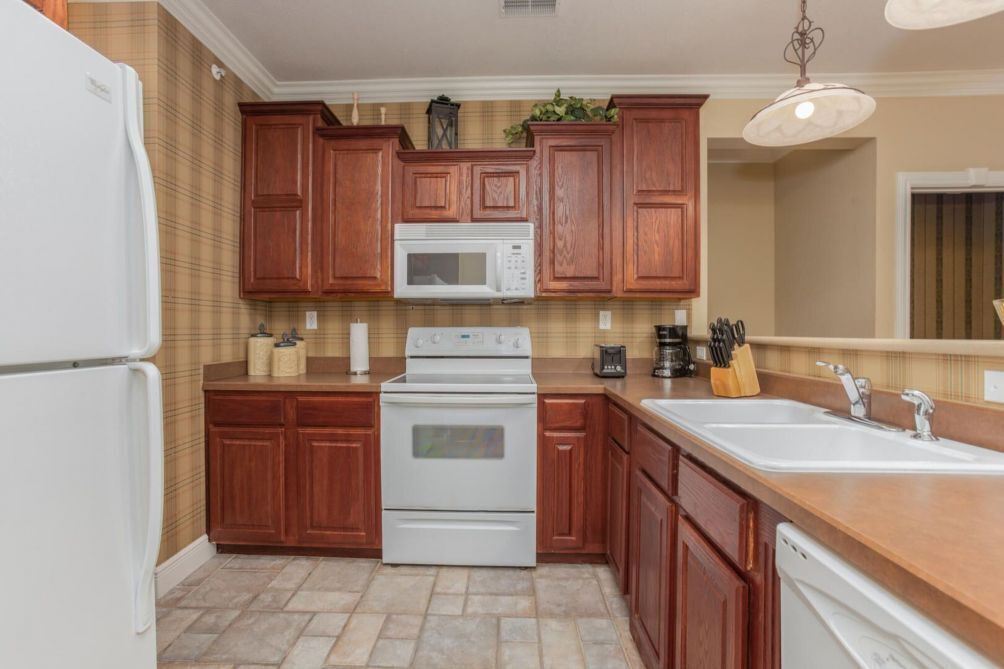 A kitchen with wooden cabinets, a white refrigerator, a microwave, a stove, and a dishwasher.