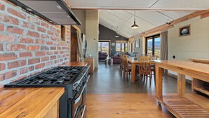 Una cocina con pared de ladrillo, estufa a gas y mesa de madera con sillas.